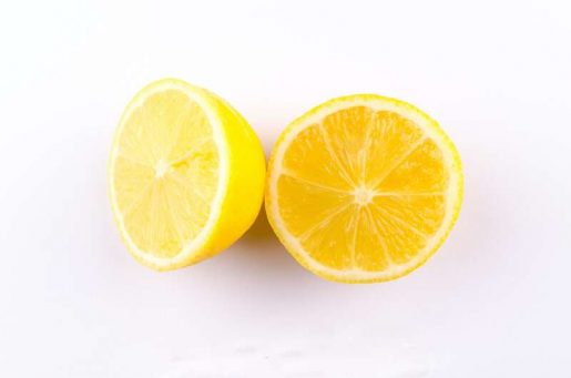 Symbolbild Tattoo entfernen Hausmittel: Zwei saftige Zitronenhälften liegen auf einem Tisch.
